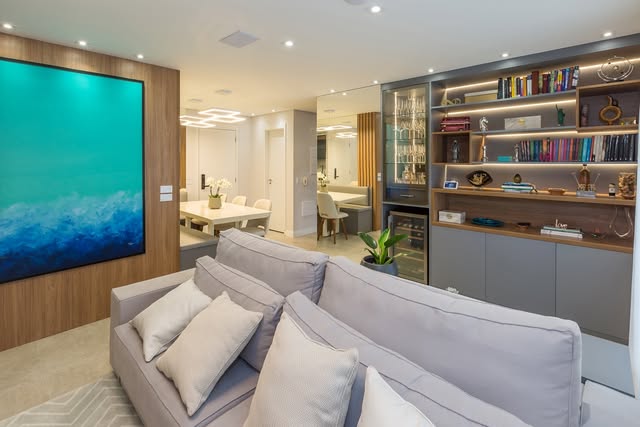 Living executado pela Atria com estante iluminada e painel em madeira